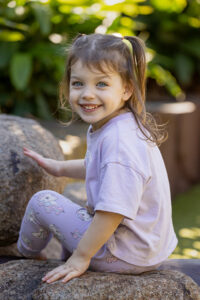 Natural smiling girl photographed in garden area during childcare photography session in Brisbane