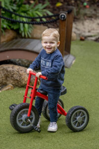 Smiling boy riding bike during natural outdoor early learning photography session in North Brisbane